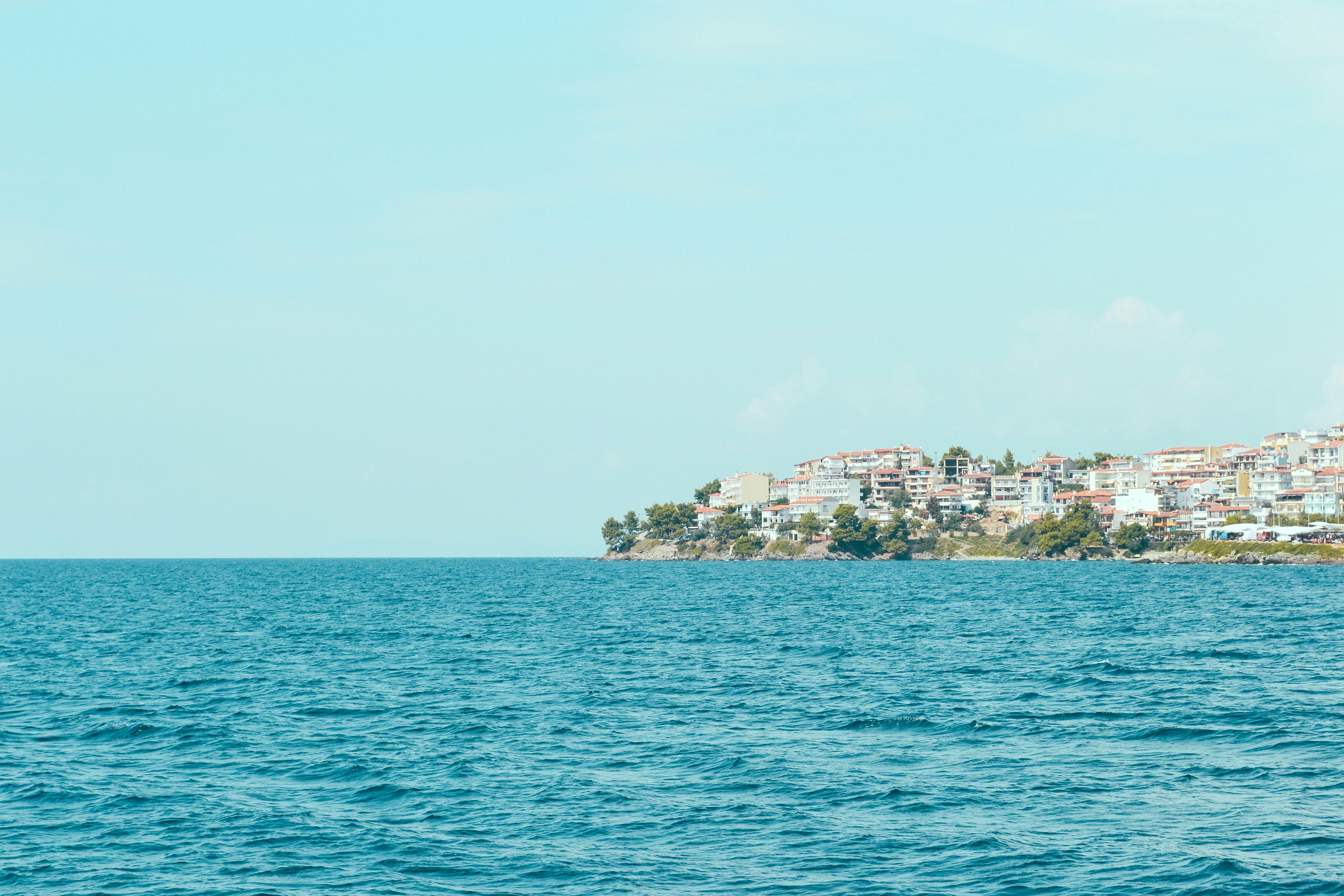 body of water near buildings on cliff